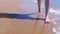 Barefooted woman tourist legs walks in water on sea waves sand beach.