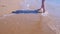 Barefooted woman tourist walks in water on sea waves sand beach, legs closeup.