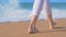 Barefooted woman walking on the beach, sea waves on background