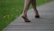 barefooted woman is walking on wood path in park at summer day, closeup of feet