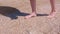 Barefooted woman walks on sea shells on sand beach makes nature feet massage.