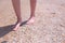 Barefooted woman walks on sea shells on sand beach makes nature feet massage.