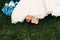 Barefooted young fair-haired bride sits on the grass in an exotic park