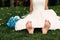 Barefooted young fair-haired bride sits on the grass in an exotic park