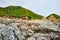 Baren rock cliff face in jagged crags with distant green mountainous hillside and overcast sky