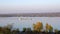 Barge floating along wide river. Colorful trees on shore, landscape