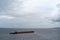 The barge floats down the river on a cloudy day.