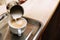 Barista adding milk to freshly brewed coffee on tray