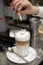 Barista decorating latte drink with cocoa powder