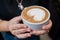 Barista girl holding fragrant freshly made cappuccino in her hands.