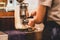 Barista grinding fresh coffee beans using coffee machine.