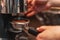 A Barista grinds coffee beans into a holder on a coffee grinder