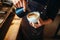 Barista hand pours cream into the cup of coffee
