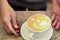 barista hand serve latte coffee in a white coffee cup with heart shape latte art on a vintage wooden table