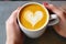 barista handcrafting a heart design on a turmeric latte
