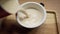 Barista makes coffee and pours a thick and fresh beverage into a mug. Hands and mug with coffee close-up