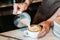 Barista pouring latte foam over coffee, espresso and creating a