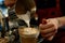 barista pouring milk into a latte, closeup