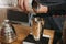 Barista preparing coffee in aeropress. Barista pours coffee grains into a steel glass.