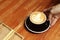 Barista putting cup of coffee on wooden table, closeup