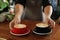 Barista putting cups of coffee on wooden table, closeup