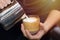 Barista`s hand is pouring milk froth into the coffee cup