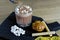 Barista sprinkles grated chocolate on cocoa with marshmallow in rock glass. Cooking Cocoa. Close-up view.