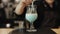 A barista stirring milk in a bar glass with a spoon. A close-up view