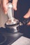 Barista tampering coffee in portafilter using tamper. Close-up fresh coffee preparation process