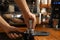 Barista tamping coffee in portafilter at bar counter, closeup