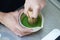 Barista Using bamboo whisk chasen stir matcha and hot water in the bowl on table, Mixing green tea in bowl