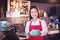 Barista wearing red color apron holding coffee cup