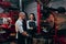 Baristas inspecting roasted coffee and woman taking notes next to coffee roast machine