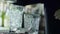 Barkeeper holds metal scoop in hands and slow strew ice cubes into transparent glass close-up on table