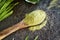 Barley grass powder on a spoon with fresh barleygrass blades