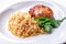 Barley porridge with meat cutlet and green-stuff close-up on white plate