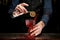 Barman in blue shirt decorates glass of splashing drink by slice of citrus