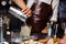 Barman in a brown leather apron pouring cocktail into the glass