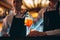 Barman hand stirring a fresh and sweet orange summer cocktail with a spoon on the bar counter.