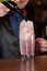 barman hands pouring red grenadine syrup into glass with alcohol cocktail and ice cubes