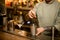 Barman holding long bar spoon and stirring cocktail in mixing cup