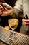 Barman holds dropper with liquid and adds it to glass with cocktail