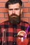 Barman with long beard and mustache and stylish hair with strict face near alcoholic cocktail, close up. Man in