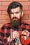 Barman with long beard and mustache and stylish hair with strict face near alcoholic cocktail, close up. Man in