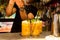 Barman making orange hurricane cocktail indoors of nightclub on top pouring sugar over green mint leaves