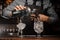 Barman pouring alcoholic drink into a glass using a jigger to prepare a cocktail