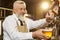 Barman pouring light beer in glass with beer tap.