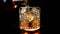 Barman pouring whiskey in the glass with ice cubes on wood table and black dark background, focus on ice cubes, whisky relax