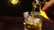 Barman pouring whiskey with ice cubes on wood table, warm atmosphere, time of relax with whisky with some light warm vintage