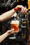 Barman pours beer into a glass goblet from the tap